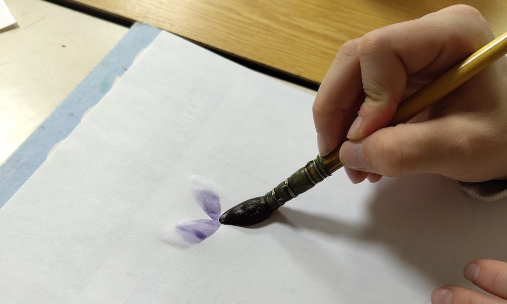 ateliers aquarelle, la main d'un enfant pose un pétale d'une fleur, périscolaire alae l'ile aux enfants d'Arbus