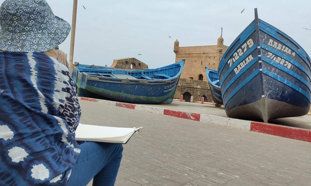 Stage au Maroc, une aquarelliste installée devant les barques aux couleurs bleu Mogador